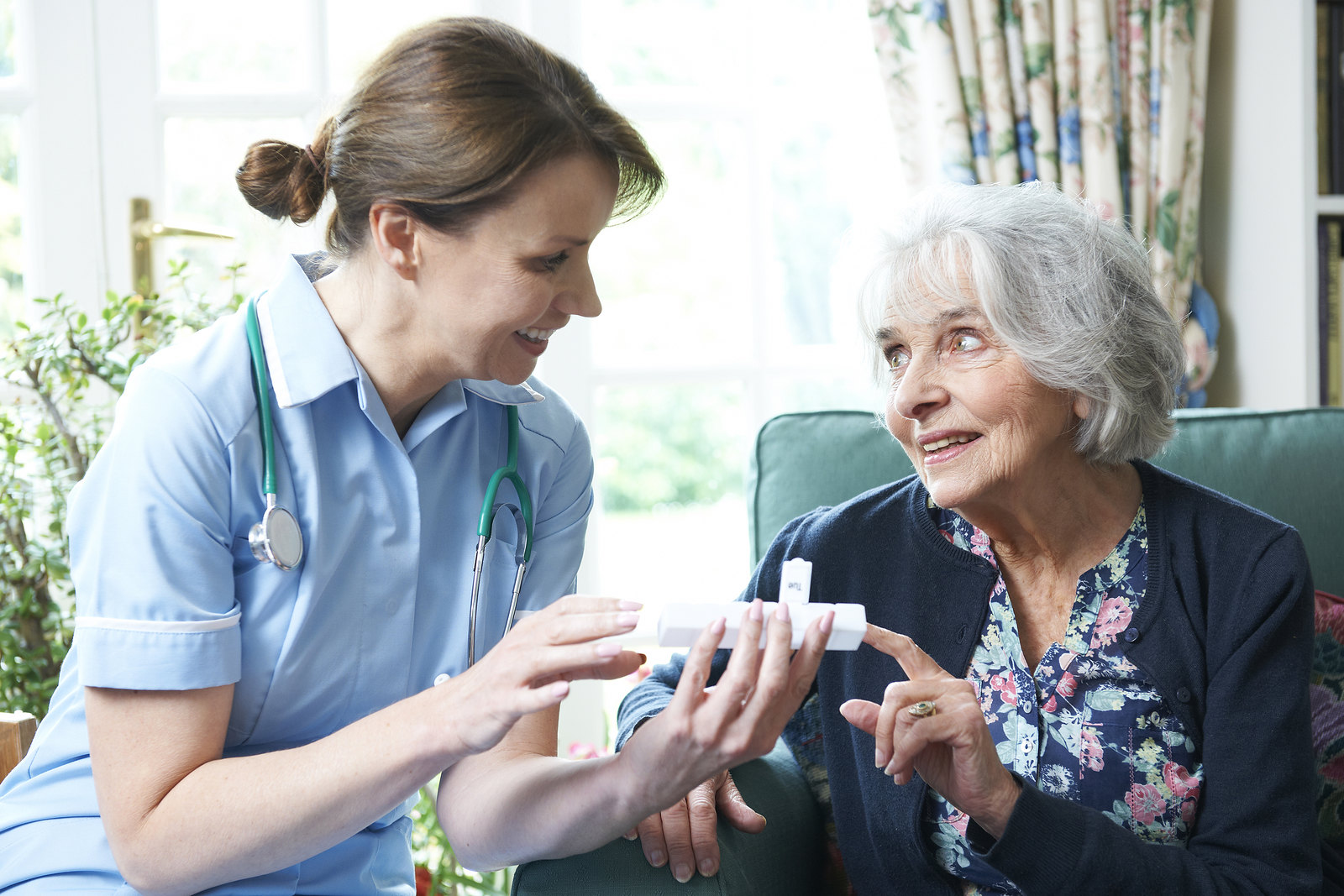 A visiting nurse helps an elderly woman with her medication.